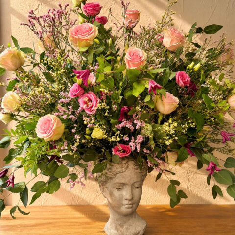 Composición floral de rosas rosas y flores silvestres sobre figura decorativa