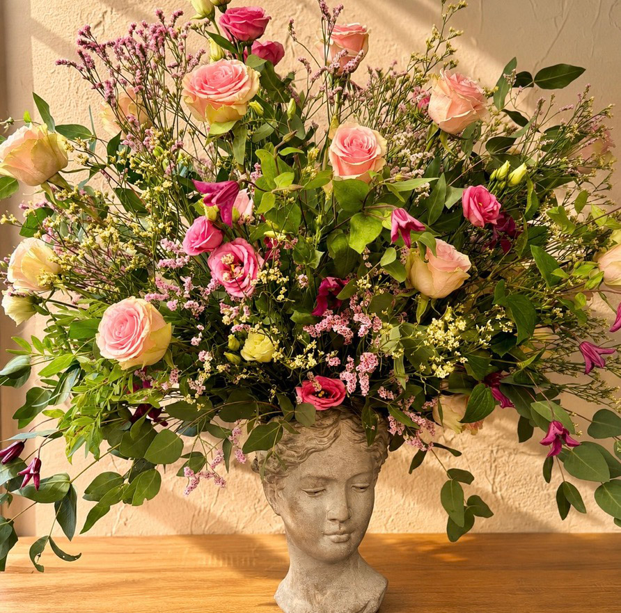Composición floral de rosas rosas y flores silvestres sobre figura decorativa